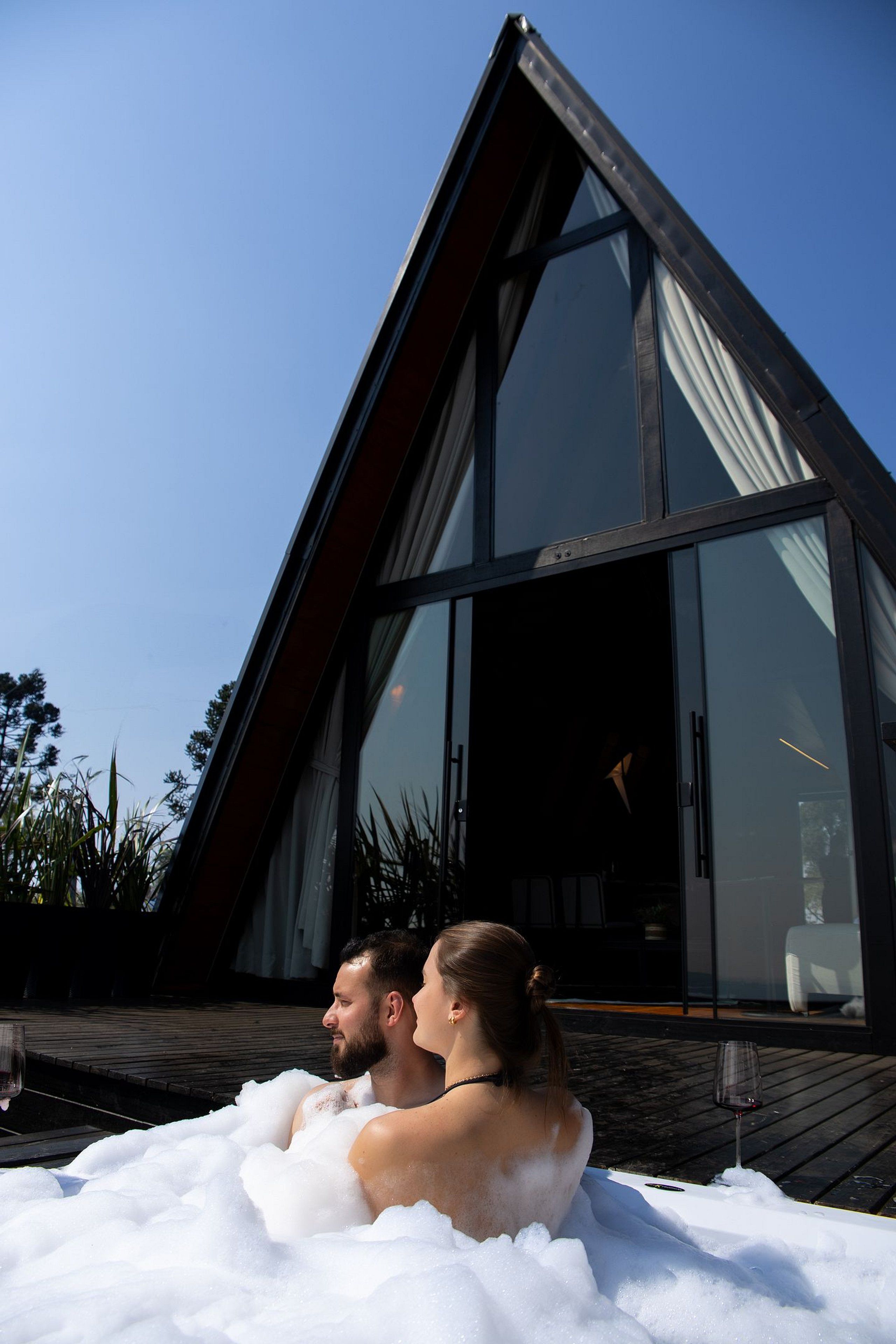 Una pareja en un jacuzzi con un edificio moderno al fondo.