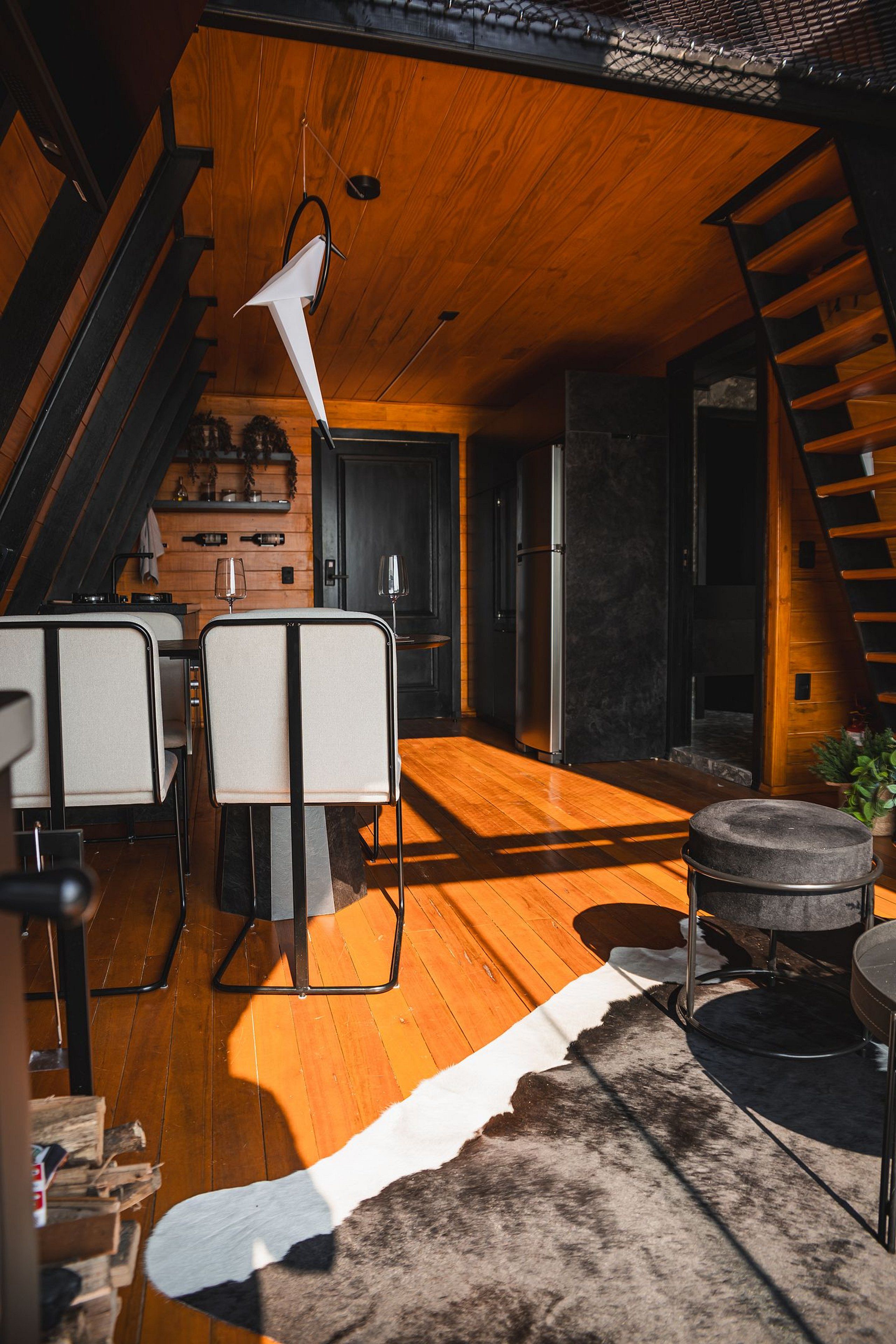 A modern kitchen with wooden cabinets, a black refrigerator, and a hanging light fixture.