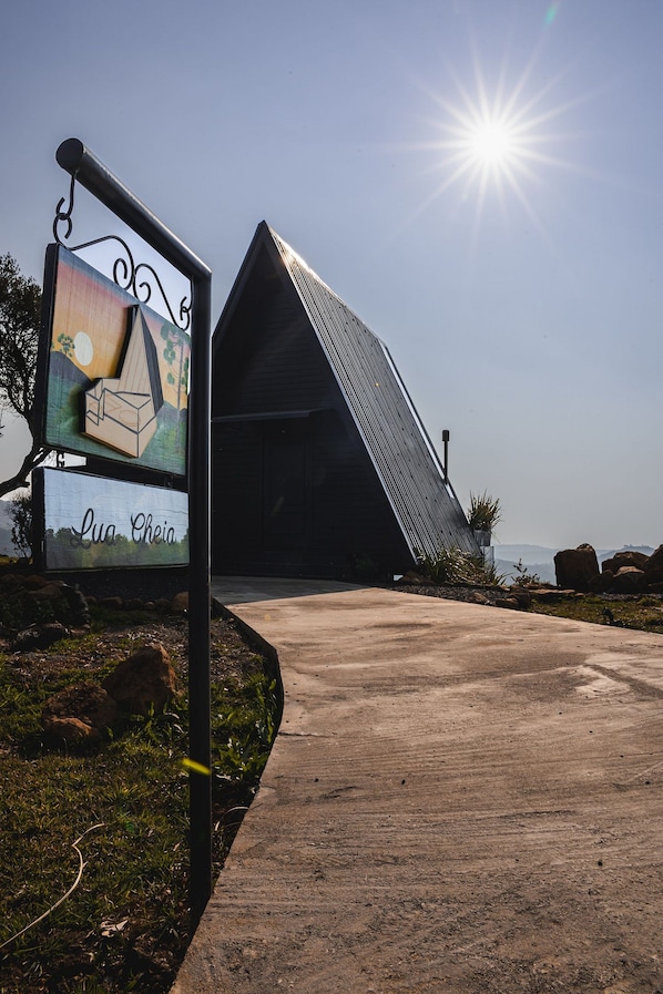 A modern building with a sloped roof and a signboard with a house illustration and the name "Lu Cheia". - Cabana Duas Faces (Urubici)