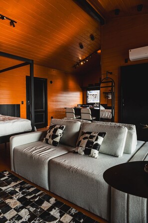A cozy room with a sofa, a bed, a dining table, and a TV. - Cabana Duas Faces (Urubici)