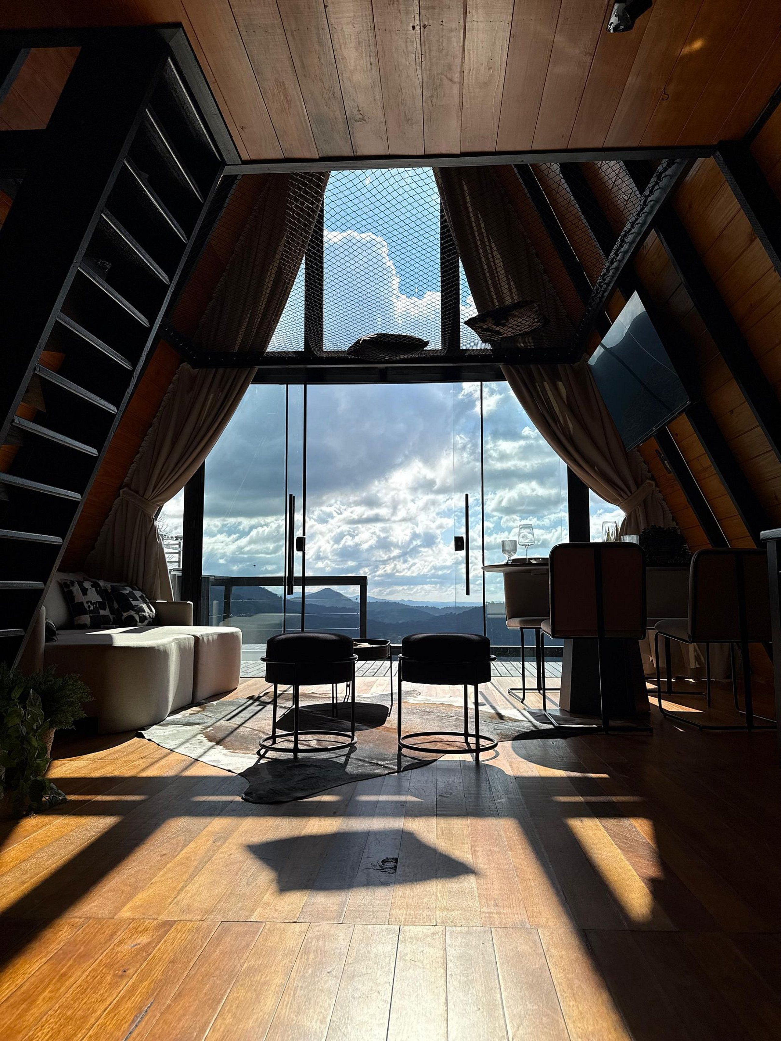 Quarto no sótão com uma janela grande, assoalho de madeira e um sofá.
