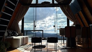 Ein Dachzimmer mit großem Fenster, Holzdielen und einer Couch.