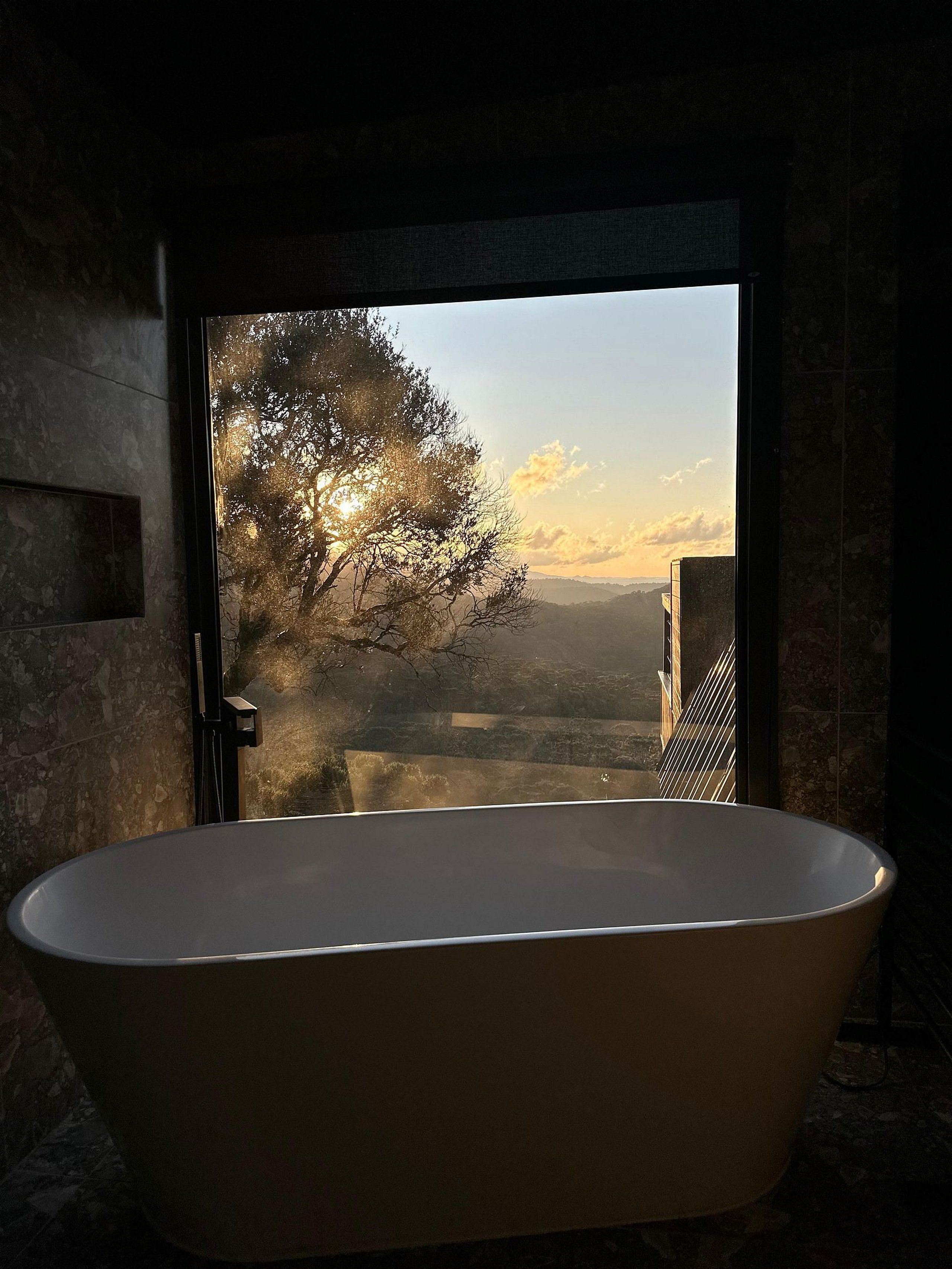 Una bañera con vista a un árbol y un paisaje lejano.