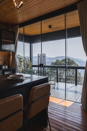 Eine moderne Küche mit einer großen Kochinsel, Holzböden und Bergblick durch große Fenster.
