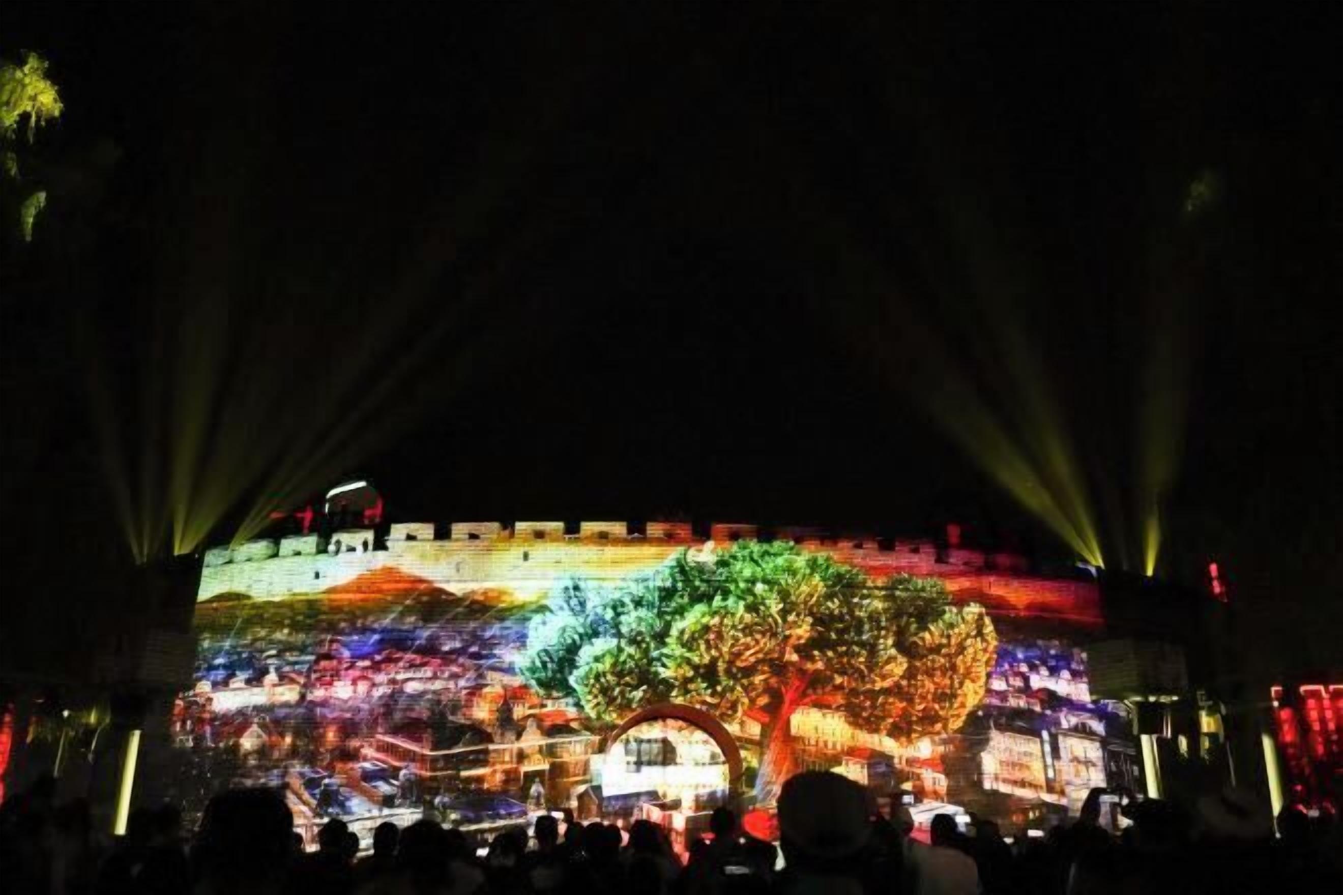 A projection of a castle scene with a large tree in the center, surrounded by a crowd of people.