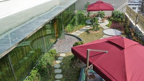 A rooftop garden with a glass wall, red umbrellas, and stepping stones. - Haopai Hotel (Shantou)
