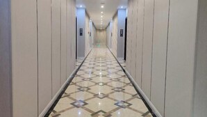 A long, narrow hallway with a patterned floor and doors on either side. - Haopai Hotel (Shantou)