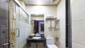 A compact bathroom with a glass shower enclosure, a sink with a mirror, and a toilet. - Haopai Hotel (Shantou)