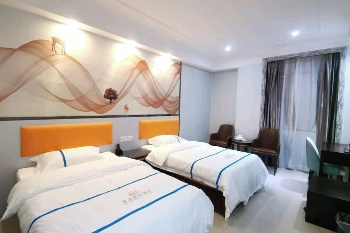A hotel room with two beds, a desk, and a chair.