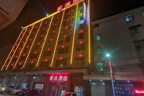 Un hotel con varios pisos, ventanas iluminadas y un cartel que indica que es un hotel.