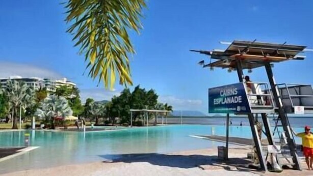 Una platja amb una piscina transparent, un lloc per al socorrista i un cartell que diu "CARNES ESPLANADE".