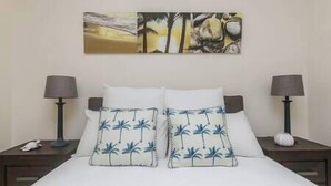 Habitació d'hotel amb un llit, dues tauletes de nit, dues làmpades i un quadre a la paret.