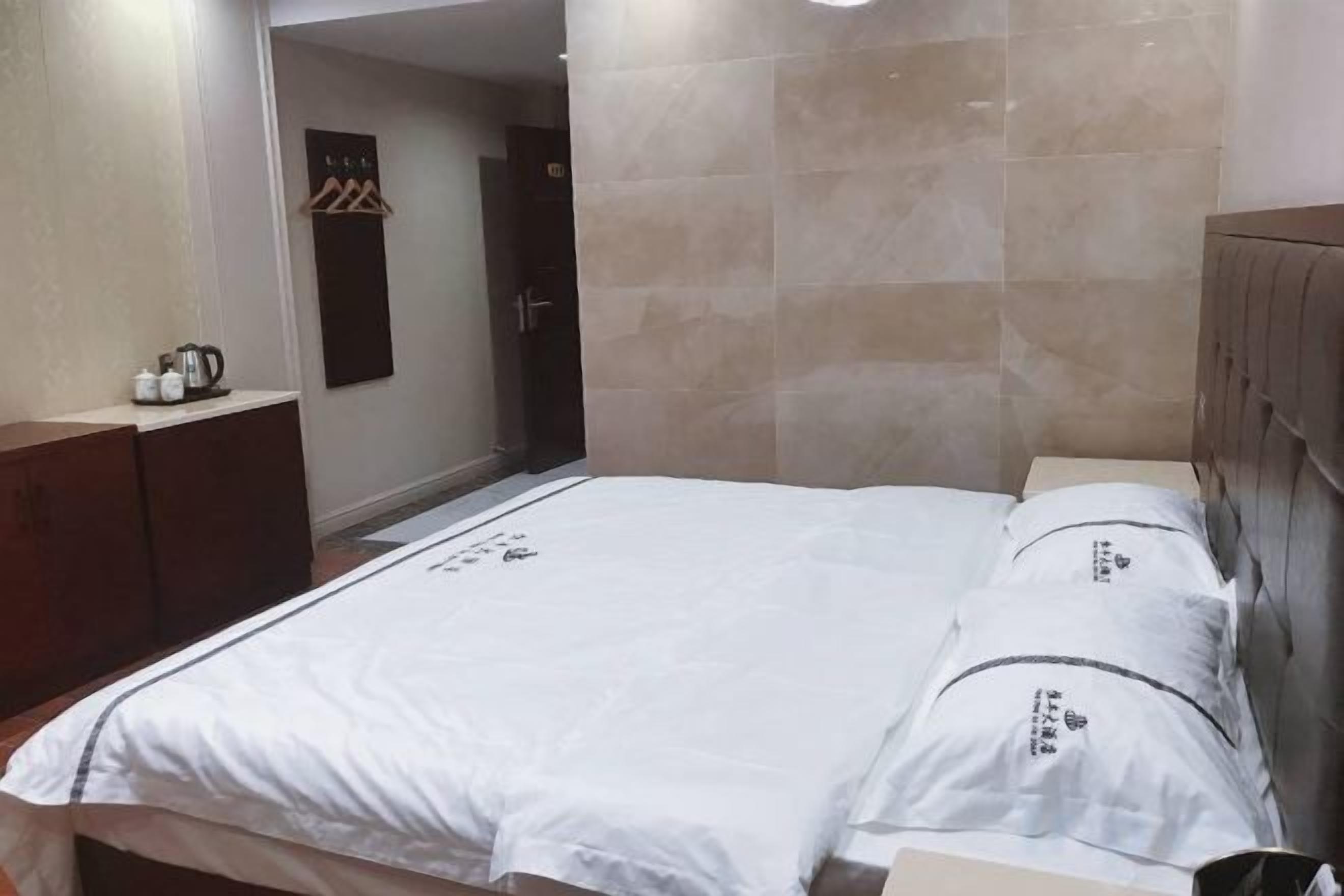 A hotel room with a bed, a wardrobe, and a small table with a kettle.