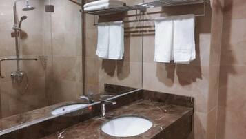 A bathroom with a sink, mirror, towel rack, and shower.