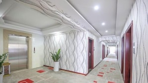 A hallway with patterned walls, a potted plant, and a red and white patterned floor. - Nanning Haoyuan Business Hotel (Nanning)