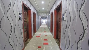 A hotel corridor with patterned walls, wooden doors, and a carpet with geometric designs. - Nanning Haoyuan Business Hotel (Nanning)