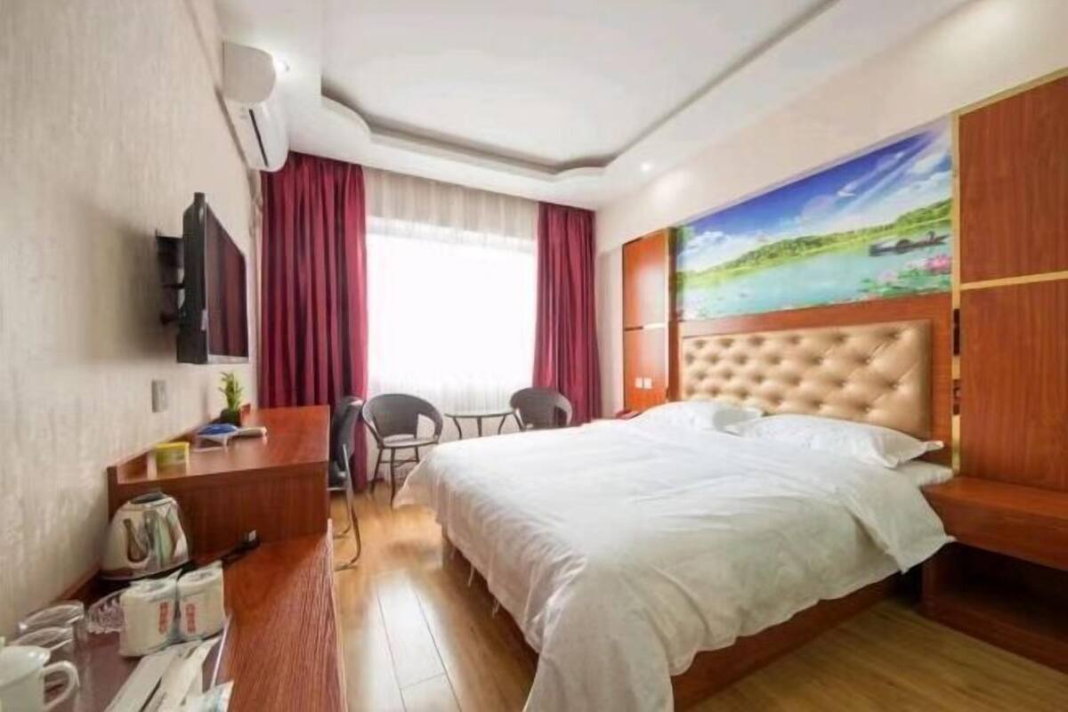 Ein Hotelzimmer mit einem großen Bett, einem Schreibtisch mit Stuhl, einem Fernseher und einem Bild an der Wand.