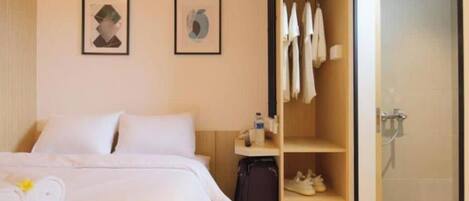 Ein Hotelzimmer mit einem Bett, einem Schrank und einem Duschbereich.