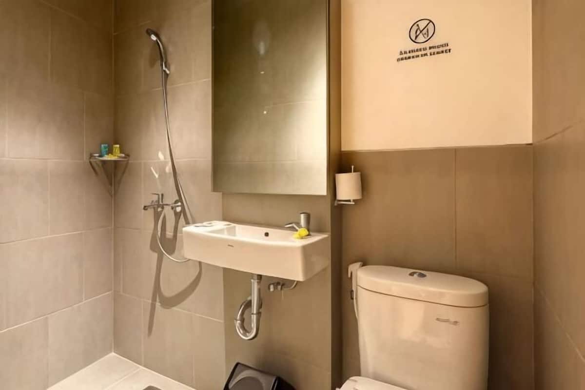 A bathroom with a shower, sink, toilet, and a mirror.