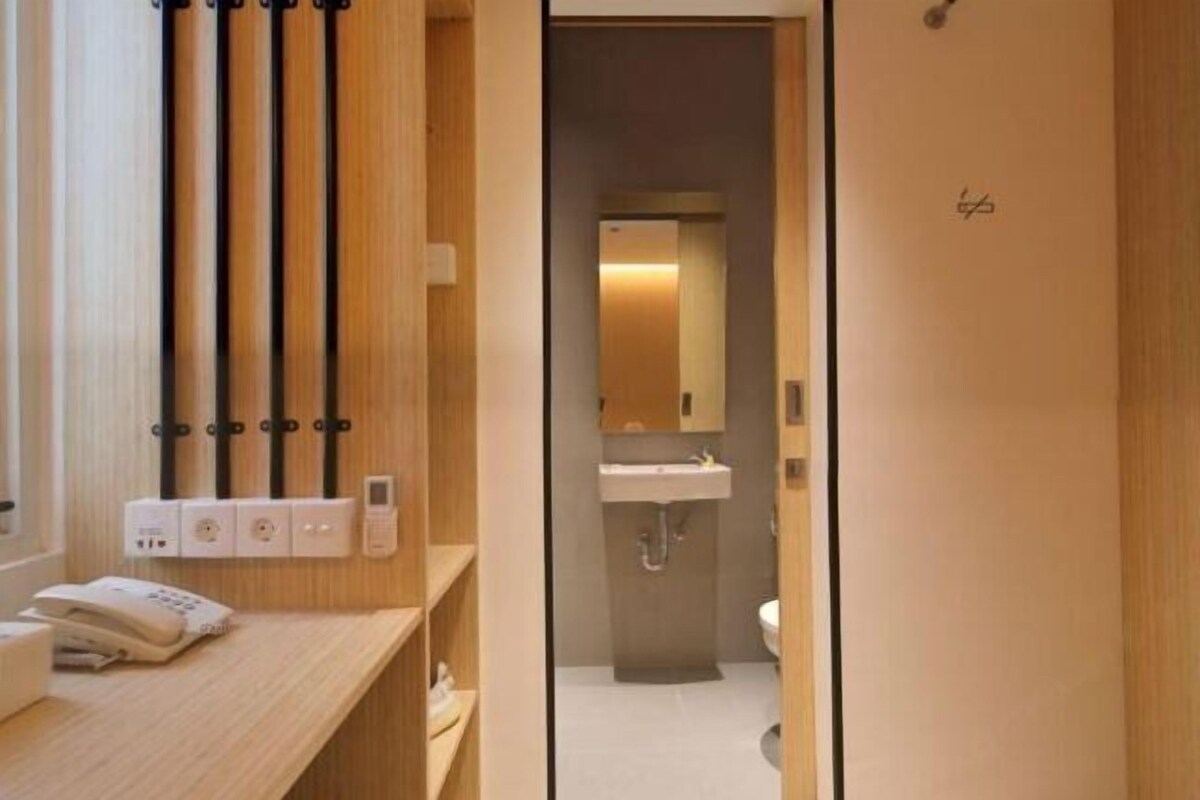 A modern bathroom with a wooden vanity, a mirror, a sink, and a toilet.