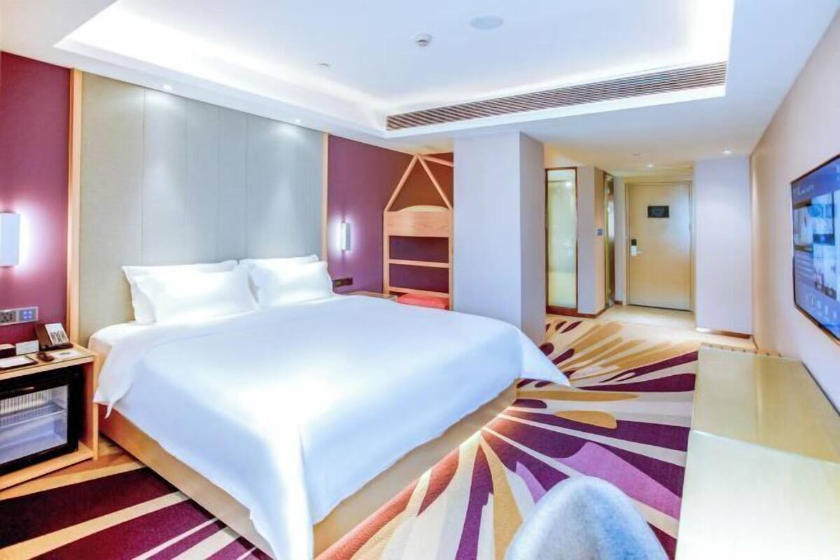 A modern hotel room with a large bed, a desk, and a TV.