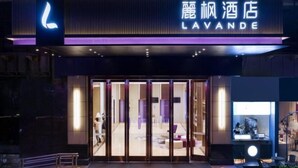 The exterior of the LAVANDE hotel with a prominent illuminated sign, a glass entrance, and a reception desk visible through the glass doors. - Lavande Hotels (Guangzhou Baiyun Yongtai Metro Station AnhuaHui) (Guangzhou)