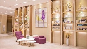 A modern interior with a seating area, shelves with decorative items, and a large abstract painting. - Lavande Hotels (Guangzhou Baiyun Yongtai Metro Station AnhuaHui) (Guangzhou)