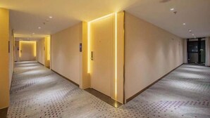 A hotel corridor with a patterned carpet, recessed lighting, and a door with a light strip. - Lavande Hotels (Guangzhou Baiyun Yongtai Metro Station AnhuaHui) (Guangzhou)