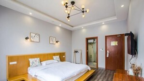Ein modernes Hotelzimmer mit einem hölzernen Bett, einem Schreibtisch und einer Deckenleuchte.