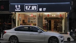 Eine weiße Limousine parkt vor einem Restaurant, das durch ein Schild als solches gekennzeichnet ist.