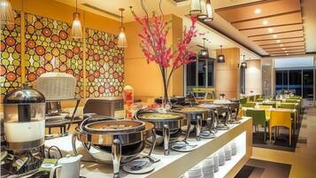 A buffet setup with multiple serving stations, a decorative wall with a circular pattern, and a modern interior design.
