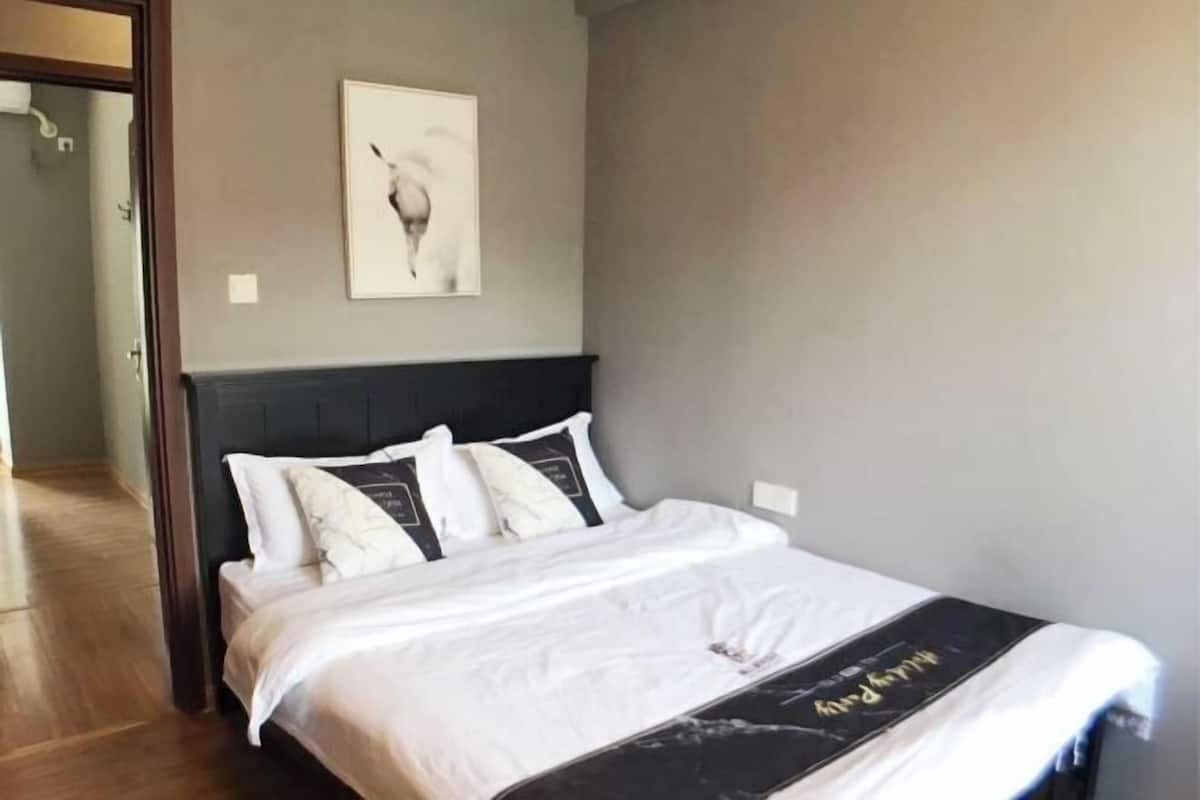Une chambre à coucher comprenant un lit, une tête de lit, une œuvre d’art accrochée au mur et une porte donnant sur une autre pièce.