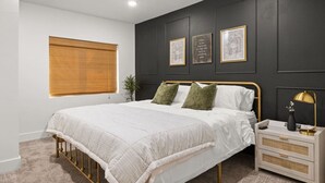 A bedroom with a bed, bedside tables, and framed pictures on the wall. - Charming 3 Bedroom Retreat: Perfect for Families, Travelers and Professionals (Billings)