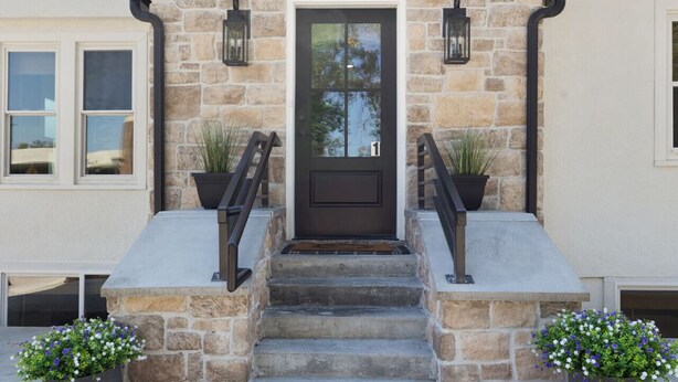 A stone house with a black door, numbered 1, and a set of stone steps leading to a small porch area. - Charming 3 Bedroom Retreat: Perfect for Families, Travelers and Professionals (Billings)