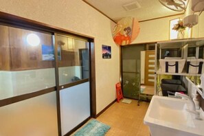 A room with a sliding door, a sink, and shelves with storage boxes. - Hanamizuki Onsen Ryokan (Ito)