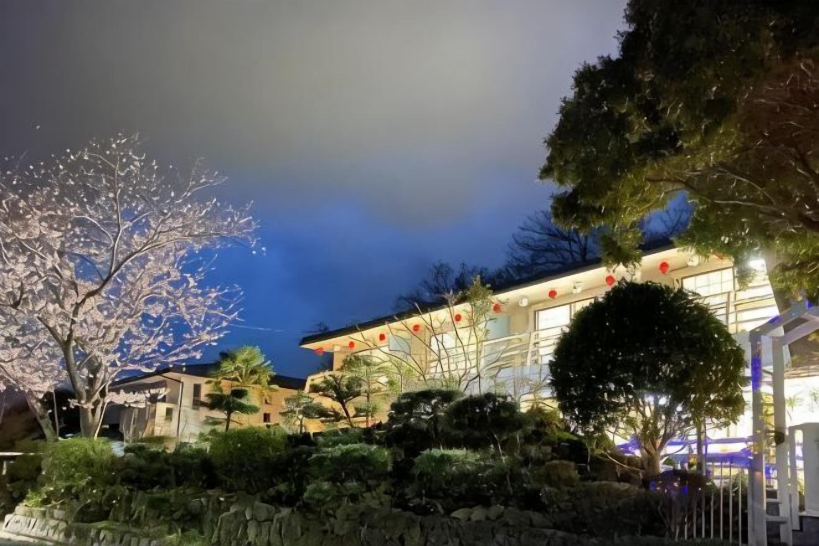 A building with a traditional architectural style, surrounded by well-maintained gardens and trees.