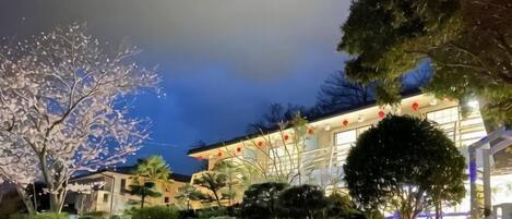 A building with a traditional architectural style, surrounded by well-maintained gardens and trees.