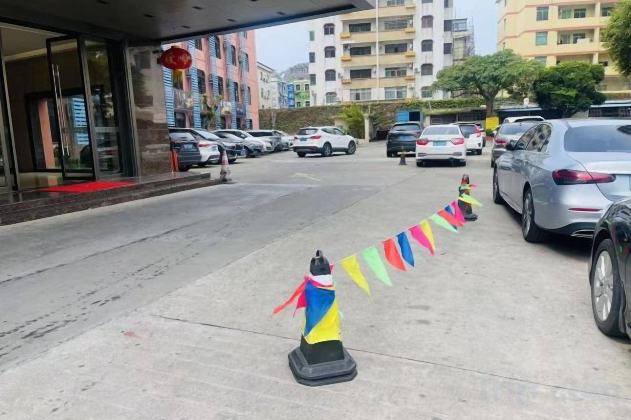 A hotel entrance with a fire hydrant, parked cars, and a building facade.