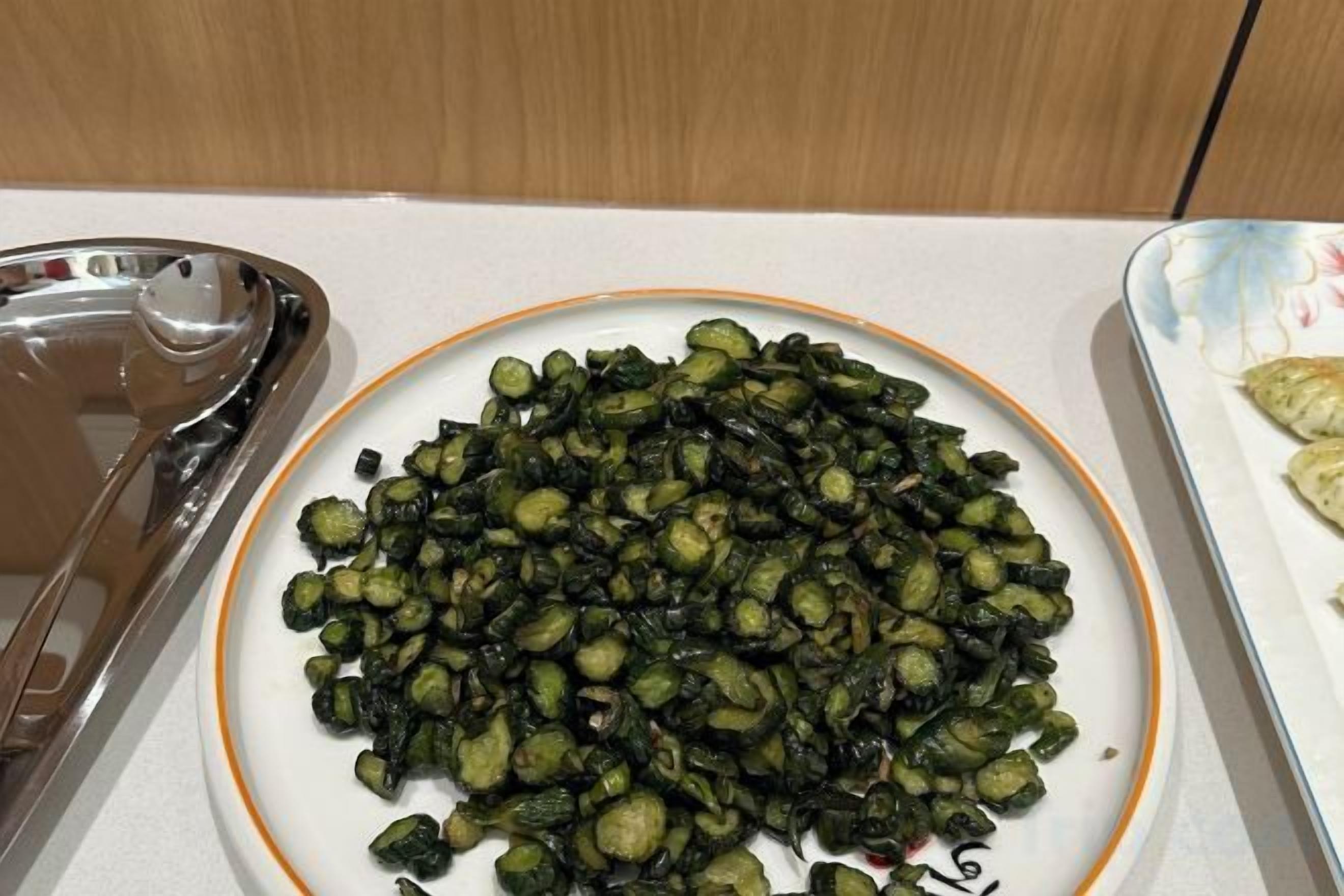 Un plato de okra cocida sobre un plato blanco con un borde anaranjado.