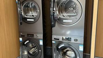 Two stacked front-loading washing machines in a commercial setting.