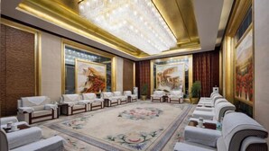 Eine luxuriöse Hotelhalle mit einem großen Kronleuchter, komfortablen Sitzmöglichkeiten und großformatigen Blumenbildern an den Wänden.