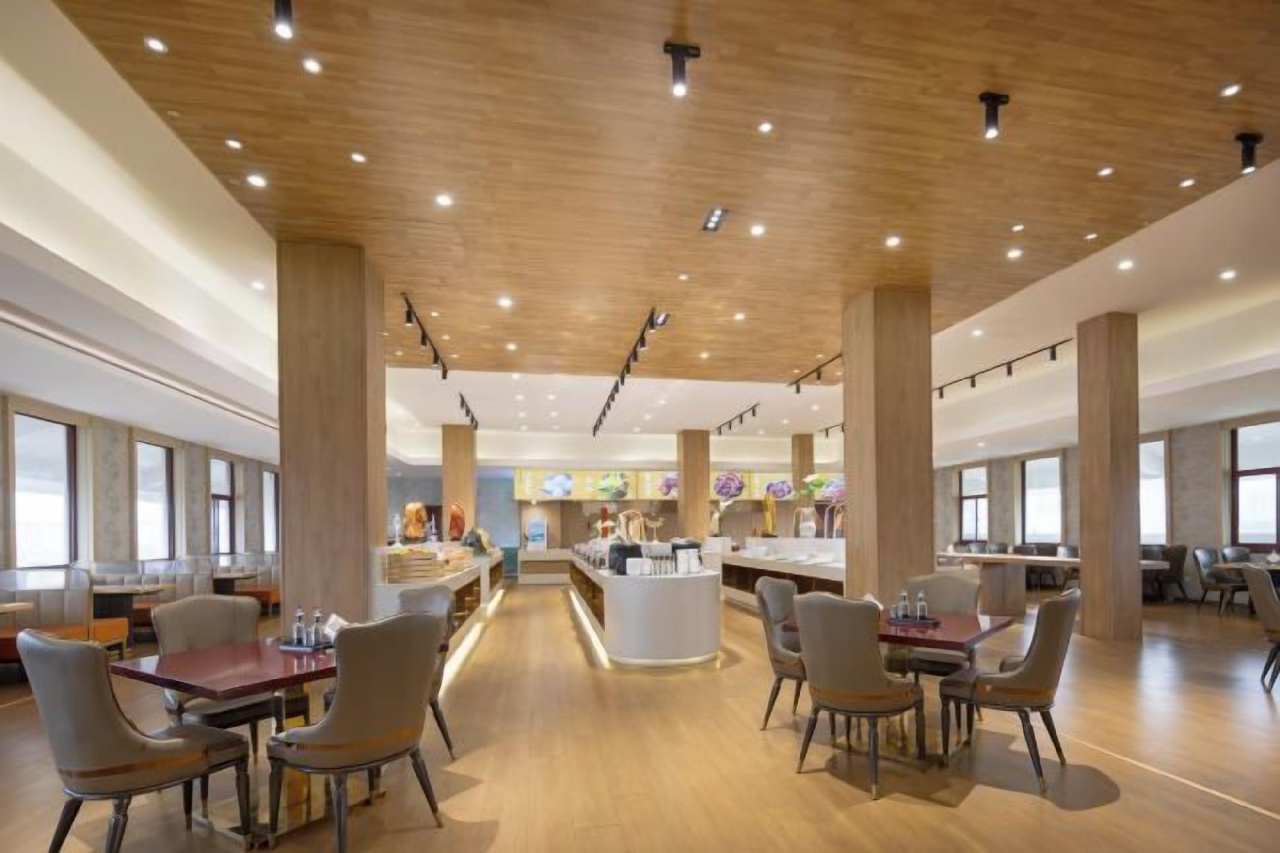 A spacious dining area with wooden flooring and high ceilings, featuring multiple tables and chairs.