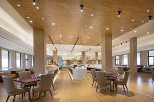 A spacious dining area with wooden flooring and high ceilings, featuring multiple tables and chairs.
