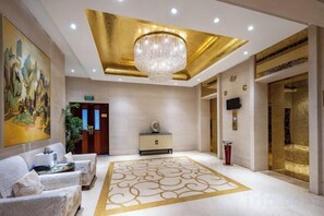 Un'accogliente hall d'hotel con un lampadario, una reception e un grande quadro appeso al muro.