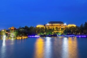 A large building with a traditional architectural style, situated by a body of water with reflections. - Liuhu Hotel (Hot Spring Garden Hotel) (Dezhou)