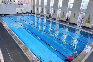 A swimming pool with multiple lanes, a lifeguard chair, and a person in the water. - Liuhu Hotel (Hot Spring Garden Hotel) (Dezhou)