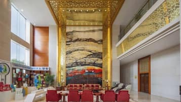 Vestíbulo de hotel con recepción, zona de estar y un mural grande.