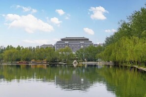 A calm lake with a reflection of a building and trees in the foreground. - Liuhu Hotel (Hot Spring Garden Hotel) (Dezhou)