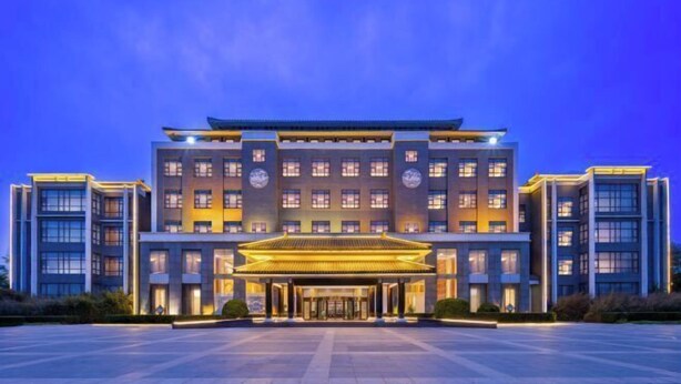 Ein modernes Hotel mit traditionellem Eingang, mehreren Etagen und einem großzügigen Parkplatz.