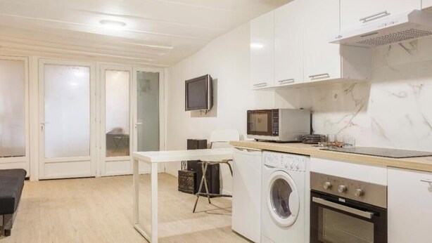 Une cuisine compacte équipée d’un four à micro-ondes, d’un four traditionnel et d’un lave-linge.